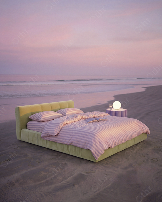 Bed With Pink Striped Bedding Placed on Sandy Beach at Sunset