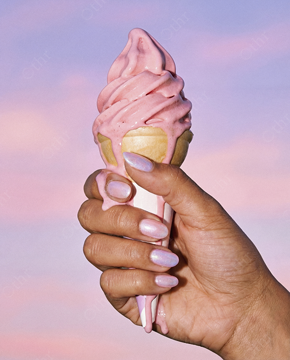 Hand Holding Pink Soft Serve Ice Cream Against Pastel Sky