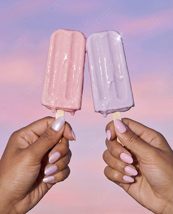 Two Pastel Ice Lollies Held Against Pink and Purple Sky