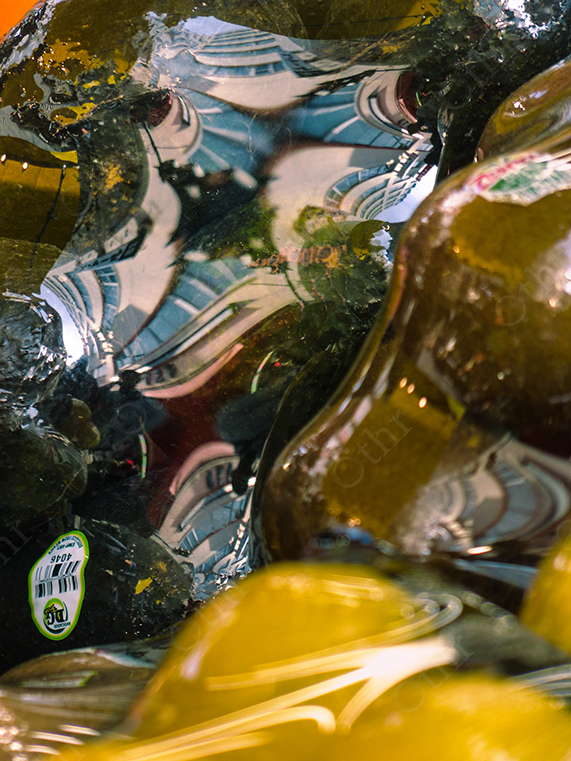 Distorted Building Reflection in Glass Bottles Among Yellow Citrus and Crushed Ice