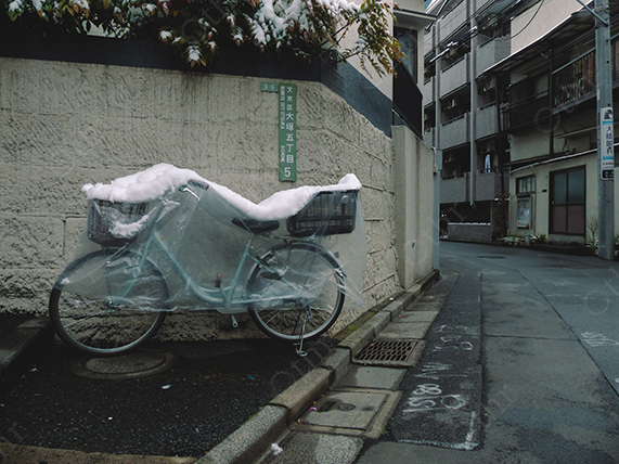 Bicycle Covered with Protective Plastic and Snow Parked Along Quiet Residential Street