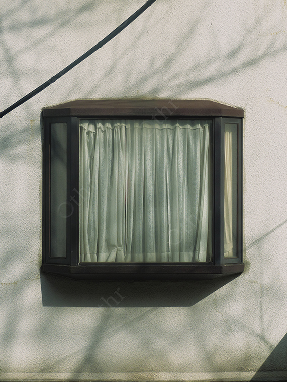 Window with Closed Curtains on Exterior Wall with Tree Shadow Patterns