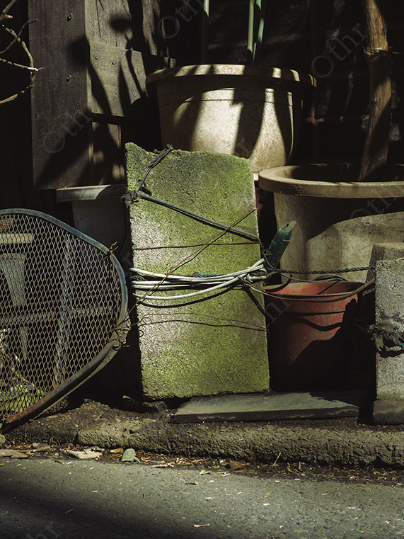 Concrete Block with Moss and Coiled Wires Among Garden Pots and Tools