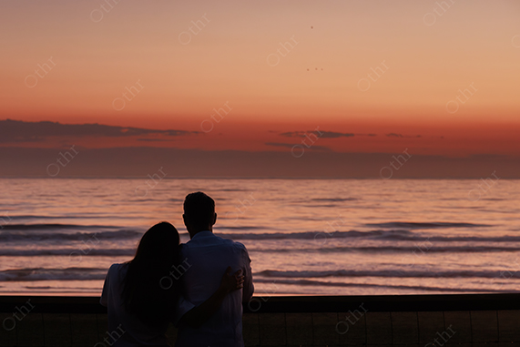 Silhouette of Couple Embracing While Watching Ocean Sunset With Orange Sky