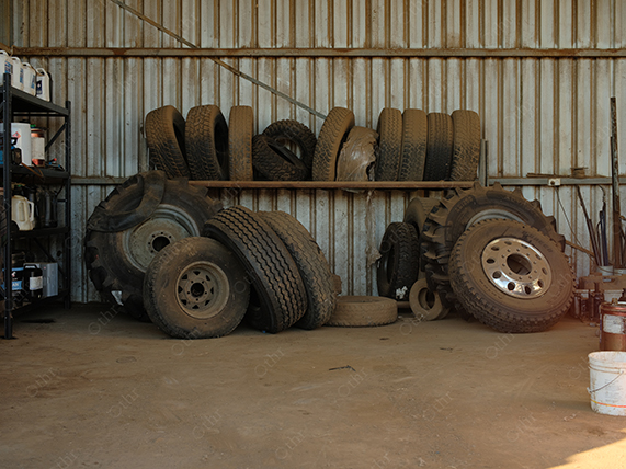 Stacked Vehicle Tyres Stored Inside Rustic Workshop With Metal Wall Background
