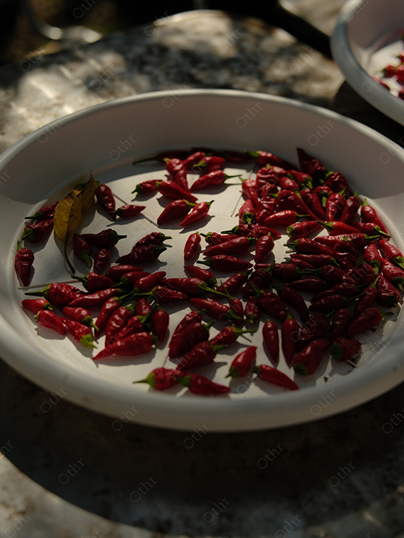 Red Chilli Peppers Spread on White Plate in Natural Sunlight With Strong Shadows