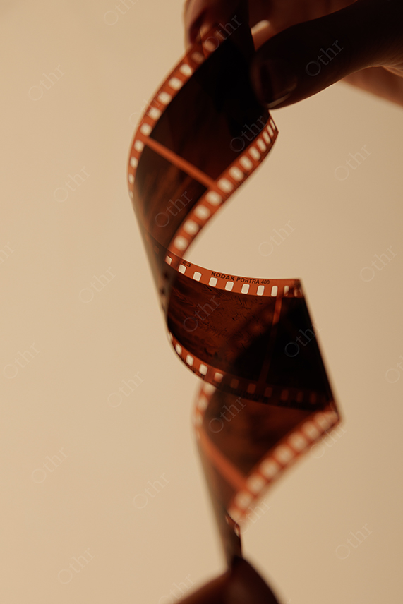 Hand Holding Curved Film Strip in Warm Light With Soft Background